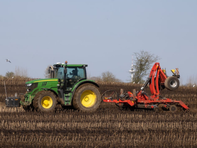 A large tractor with a harvester attached sits in a field