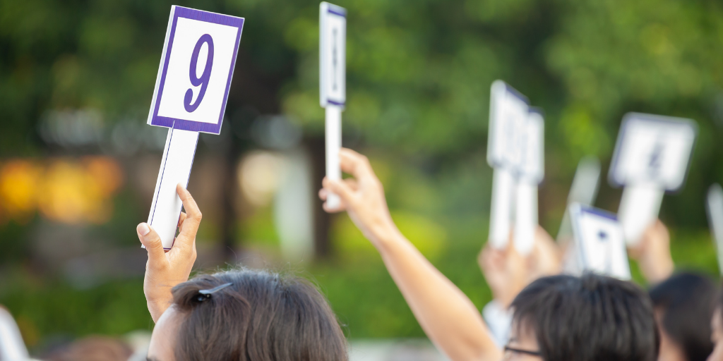 auction buyers holding bidding signs